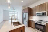 Located at 333 W 24th St in Houston's desirable Timbergrove neighborhood, this well-designed 2-bedroom, 1-bathroom unit offers a clean, modern aesthetic throughout its efficiently arranged single-floor layout. Light wood flooring flows seamlessly through the open living areas, complemented by crisp white walls and abundant natural light.

The open-concept kitchen is a standout feature, boasting white shaker cabinetry extending to the ceiling, a light blue subway tile backsplash, quartz countertops, and a large center island with a farmhouse sink and pendant lighting above. Stainless steel appliances — including a French door refrigerator, range, microwave, and dishwasher — complete this functional and stylish space. The kitchen opens directly into the living area, which features French doors with transom windows that invite natural light and provide outdoor access.

Both bedrooms are bright and calm, featuring light wood flooring, white walls, and multiple windows with blinds that offer neighborhood views. The primary bedroom provides a comfortable footprint with easy access to the shared bathroom.

The bathroom is elegantly appointed with large-format marble-look tile flooring, a wide double-sink vanity with a backlit mirror, a glass-enclosed shower, and access to a dedicated closet with built-in shelving. Paneled interior doors and recessed lighting add refined finishing touches throughout.