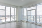 Located at 40 Lagerfeld Dr in Brampton, Ontario, this modern 2-bedroom, 1-bathroom unit offers a bright and contemporary living experience. The open-concept kitchen and living area is anchored by a sleek kitchen featuring white cabinetry, stainless steel appliances including a built-in microwave, stainless refrigerator, and gas range, complemented by a taupe quartz peninsula and glossy tile backsplash. Track lighting and light wood-tone flooring extend throughout, creating a clean, cohesive aesthetic. In-suite stacked laundry is conveniently integrated into the kitchen area. The living space is bathed in natural light through expansive floor-to-ceiling windows and sliding glass doors that open to a private balcony, offering sweeping views of the surrounding Brampton cityscape. Both bedrooms are well-proportioned, featuring large windows with city views and light hardwood flooring. The primary bedroom benefits from direct balcony access, while the second bedroom includes a tall vertical window framing outdoor scenery. A dedicated closet provides additional storage. The bathroom is finished with clean white tile, a glass-enclosed tub and shower, and chrome fixtures. The unit's crisp white palette and modern design create a bright, airy ambiance throughout.