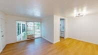 Located at 2131 N Cahuenga Blvd in the Hollywood Hills neighborhood of Los Angeles, this 1-bedroom, 1-bathroom apartment offers 520 square feet of efficiently designed single-floor living. Light wood flooring runs throughout the main living areas, creating a warm and cohesive aesthetic against crisp white walls.

The living room is a bright, open space featuring a wall-mounted heater unit, recessed lighting, and a large sliding glass door with a window treatment that invites natural light. The galley-style kitchen is a standout, outfitted with white shaker cabinetry, white subway tile backsplash, light countertops with a double basin sink and matte black faucet, and stainless steel appliances including a gas range and refrigerator.

The 140-square-foot bedroom features light wood flooring, a ceiling fan, built-in closet storage with upper cabinetry, and a window offering outdoor views of surrounding greenery. The bathroom includes a full tub and shower combination with floor-to-ceiling white subway tile and a trio of windows above the tub for natural ventilation. A connecting hallway ties the layout together, making efficient use of the unit's compact footprint.