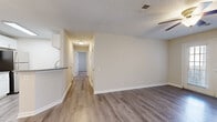 Located at 1150 Sigman Rd NE in Conyers, Georgia, this single-floor residence offers a clean, well-maintained interior with a consistent neutral color palette throughout. The main living area features durable wood-look plank flooring, a textured ceiling, ceiling fan, and an open sightline down a central hallway that connects to the private rooms. The galley-style kitchen is thoughtfully appointed with white shaker cabinetry, granite-look countertops, a stainless steel appliance suite including a range, microwave, refrigerator, and dishwasher, and light wood-look flooring that ties the space together cohesively. The bedrooms are finished with plush carpeting and ceiling fans, providing a comfortable retreat. One bedroom includes a generously sized walk-in closet outfitted with wire shelving for added storage capacity. The bathroom features a white vanity with granite countertops and a full tub-shower combination with stainless steel grab bars. Outside, a covered patio area overlooks a landscaped setting with mature trees, offering a pleasant outdoor space. The exterior is clad in neutral siding, complemented by shuttered windows and wall-mounted lighting.