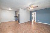 Located at 6407 10th Ave in the Hyde Park neighborhood of Los Angeles, this single-floor, 2-bedroom, 1-bathroom home offers a practical and comfortable layout. Consistent terracotta-toned tile flooring runs throughout the entire space, providing a cohesive and easy-to-maintain finish. The bedrooms are painted in a calming blue-gray palette and feature ceiling fans with integrated lighting, wall-mounted air conditioning units, and windows fitted with horizontal blinds that allow natural light to filter in. The primary bedroom is a well-proportioned room with a closet and an open doorway connecting to the rest of the home. The second bedroom offers similar features, including a window overlooking the exterior greenery. The full bathroom includes a dark-cabinet vanity with a white basin, a tub/shower combo with white tile surround, and terracotta tile flooring. The kitchen is equipped with gray cabinetry, a mosaic tile backsplash, countertop workspace, and includes a stainless steel refrigerator, with a window that brings in natural light. The living area provides an open, versatile space to complete this efficiently designed single-level home.