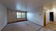 Located at 3130 Eldorado Blvd in Eau Claire, Wisconsin, this single-floor, 2-bedroom residence offers a functional and straightforward layout designed for comfortable everyday living. The combined kitchen and living room area serves as the heart of the home, where warm wood-toned cabinetry, laminate countertops, and a peninsula with a built-in sink define the kitchen space. White appliances, including an electric range and refrigerator, complement the oak cabinetry, while durable hardwood-style flooring runs throughout this area. The living room portion transitions seamlessly, providing an open, versatile space with natural light filtering through a window overlooking the surrounding neighborhood. Both bedrooms are carpeted and generously proportioned, with the primary bedroom offering a built-in closet system featuring shelving and drawers for organized storage. Each bedroom benefits from windows that bring in natural light and views of the lush greenery outside. Baseboard heating is present throughout, ensuring warmth during Wisconsin winters. A wall-mounted air conditioning unit in the main bedroom provides additional climate control. The neutral color palette and clean lines throughout create a practical, move-in-ready environment suited for a variety of lifestyles.