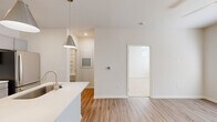 This thoughtfully designed one-bedroom, one-bathroom residence offers an efficient and comfortable single-floor layout. The open-concept living area seamlessly integrates the kitchen, dining, and living spaces, creating an inviting, airy atmosphere. The kitchen is outfitted with gray shaker-style cabinetry, white quartz countertops, a subway tile backsplash, stainless steel appliances including a range, over-the-range microwave, and refrigerator, and a peninsula with an undermount sink accented by modern pendant lighting. Light wood-look flooring runs throughout the main living areas, contributing to a clean, contemporary aesthetic.

The bedroom features plush carpeting, a ceiling fan, and multiple windows fitted with horizontal blinds that allow for natural light and privacy. The space is supported by four closets, including a walk-in closet with wire shelving, offering generous storage capacity. A dedicated pantry and utility room add further practicality to the layout.

The bathroom includes a full tub-shower combo with tiled surround, a single-sink vanity with gray cabinetry, and recessed lighting. A private balcony extends the living space outdoors, offering pleasant views of a landscaped community courtyard and pool area.