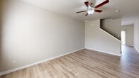 This two-story home offers a thoughtfully designed layout spread across two well-proportioned floors. The main level features a bright and open living room with light wood-look flooring and a ceiling fan, a dedicated dining area with a modern multi-light chandelier, and a kitchen equipped with dark espresso cabinetry, granite-style countertops, subway tile backsplash, and stainless steel Whirlpool appliances including a side-by-side refrigerator and electric range. A half or full bathroom on the main level adds convenience, and the open staircase connects seamlessly to the upper floor. Upstairs, the generous primary bedroom benefits from multiple windows that invite natural light, complemented by plush carpeting. It is accompanied by a spacious walk-in closet outfitted with wire shelving systems providing ample storage. The primary bathroom features wood-look flooring, a dark-toned vanity with a white countertop, a large mirror, and a glass-enclosed walk-in shower. Two additional carpeted bedrooms each include double-door closets. The secondary bathrooms maintain the same clean, neutral aesthetic with hardwood-style flooring throughout. The home's consistent warm neutral palette, ceiling fans, and abundant natural light create a comfortable and cohesive living environment.