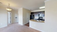 This 1-bedroom, 1-bathroom residence is thoughtfully laid out across a single floor, offering a comfortable and functional living environment. The open-concept design connects the kitchen and living area seamlessly, creating an inviting, cohesive space.

The kitchen is well-appointed with dark espresso cabinetry providing ample storage, light granite-style countertops, and a full suite of black appliances including a refrigerator, electric range, over-the-range microwave, and a double-basin sink set into a peninsula that faces the living area. Hardwood-style flooring runs throughout the kitchen, adding warmth and easy maintenance.

The living area is generously sized, featuring plush wall-to-wall carpeting, crown molding, and a ceiling fan with integrated lighting. A pendant light fixture near the kitchen transition adds an additional design touch. The space is bright and open, with clean neutral wall tones throughout.

The bathroom is well-equipped with a long vanity countertop, dual medicine cabinets, a wide illuminated mirror, dark navy cabinetry, and hardwood-style flooring. The layout also includes a dedicated hallway connecting the bedroom and bathroom for added privacy. The overall design is clean, practical, and move-in ready.
