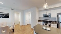 This single-floor residence offers a thoughtfully designed layout with a clean, contemporary aesthetic defined by crisp white walls, light wood-style flooring in the main living areas, and recessed lighting throughout. The open-concept kitchen is a functional centerpiece, equipped with stainless steel appliances—including a gas range, built-in microwave, and full-size refrigerator—paired with white cabinetry and dark countertops. A peninsula with seating and pendant lighting above serves as a natural transition into the dining area, which benefits from generous natural light through large sliding glass doors fitted with vertical blinds. The living room is an intimate yet comfortable space, featuring a window with blinds and warm, neutral tones. Two bedrooms provide restful retreats, each fitted with plush carpeting, ceiling fans, and ample natural light. One bedroom includes direct access to a bathroom with a vanity, dark countertop, and a tub-shower combination. The second bathroom mirrors this clean, functional design, also featuring a tub-shower combination, wood-style flooring, and a window for natural ventilation. The overall ambiance is modern, bright, and welcoming.