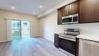 Located at 6916 Fulton St in San Diego, CA, this single-floor unit showcases a contemporary design with a clean, neutral color palette throughout. Light wood-style flooring runs consistently across all living areas, complementing the warm beige walls and crisp white trim for a cohesive, modern aesthetic.

The kitchen is well-appointed with rich dark-walnut cabinetry offering ample upper and lower storage, white countertops, and a full suite of stainless steel appliances including an electric range, over-the-range microwave, and dishwasher. A single-basin sink with a modern faucet completes the functional layout.

The living area is generously sized with recessed lighting and a sliding glass door that provides direct access to an outdoor space, allowing natural light to fill the room. Additional rooms offer flexible use, each featuring the same wood-style flooring, neutral walls, and windows that bring in natural light.

The bathroom includes a dark-walnut vanity with a white countertop, a mirrored medicine cabinet, and a full tub-shower combination with brushed nickel fixtures and tiled surround. The entry foyer houses an electrical panel and features a teal-accented front door with a door closer mechanism.