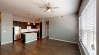 This 2-bedroom, 2-bathroom B3 floor plan presents a thoughtfully designed single-story layout that balances open communal spaces with private retreats. The open-concept living and dining area features rich hardwood-style flooring, neutral gray walls, and a ceiling fan, creating a versatile and inviting environment. Large windows in the living area allow natural light to fill the space.

The kitchen is a standout feature, equipped with dark espresso cabinetry extending to the ceiling, stainless steel appliances including a refrigerator, dishwasher, and microwave, and a white subway tile backsplash. A granite-topped center island provides additional prep space and casual seating, while pendant and track lighting enhances the kitchen's modern aesthetic.

Both bedrooms are carpeted and feature ceiling fans and windows with outdoor views, providing a comfortable, quiet atmosphere. One bedroom includes hardwood-style flooring and dual windows for added brightness.

The two bathrooms are finished consistently, each featuring dark wood vanities with granite countertops, tub-shower combinations with tile surrounds, and hardwood-style flooring, offering a clean and modern feel throughout.