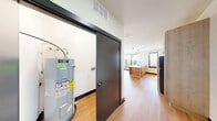 Located at 330 S Shelby St in downtown Louisville, KY, this 2-bedroom, 2-bathroom unit offers a thoughtfully designed layout across a single floor. Light hardwood flooring runs throughout, complemented by crisp white walls and bold black door frames that create a clean, contemporary aesthetic.

The open kitchen serves as a central highlight, featuring light maple cabinetry, white subway tile backsplash, stainless steel appliances including a full-size refrigerator and electric range, and a freestanding island with a white quartz countertop and built-in shelving. Pendant lighting and large black-framed windows allow natural light to pour in, offering views of the surrounding Louisville neighborhood.

The living area is open and bright, flowing naturally from the kitchen. Both bedrooms feature warm hardwood flooring, dedicated closet space, and bold black-trimmed sliding or hinged doors. The primary bedroom is generously sized, with two large windows that frame outdoor views and fill the room with sunlight.

Each bathroom is finished with white subway tile tub surrounds, matte black fixtures, and striking hexagonal floor tile. The unit also includes a dedicated laundry area and in-unit utility access, adding everyday convenience to this stylish urban residence.