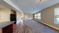 This single-floor residence offers a practical and comfortable layout designed for everyday living. The open-concept living area serves as the heart of the home, featuring rich hardwood-style flooring that transitions seamlessly into plush carpeting, warm beige walls, and multiple windows fitted with roller shades that allow for an abundance of natural light.

The kitchen is well-equipped with rich cherry wood cabinetry, dark granite-style countertops, a full suite of black appliances including a gas range, over-the-range microwave, and refrigerator, along with a convenient breakfast bar that connects the kitchen to the main living space.

The bedrooms are generously sized, each featuring soft wall-to-wall carpeting, neutral-toned walls, and windows that bring in natural light. One bedroom includes a walk-in closet with built-in shelving, offering practical storage solutions.

The bathroom is finished with warm beige tile flooring, a rich wood vanity with a white countertop and large mirror, and a shower equipped with accessibility grab bars, reflecting a thoughtful, inclusive design.

Throughout the space, consistent warm neutral tones, white trim, and clean lines create a cohesive and inviting atmosphere suited for comfortable daily living.