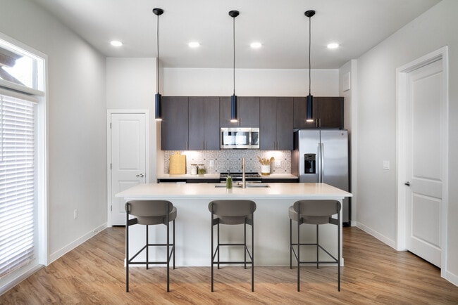 Kitchens with stainless steel appliances, wine fridges, quartz countertops, tile backsplash, and hard surface flooring - Avalon Townhomes at Bee Cave