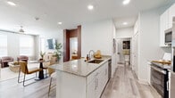 This thoughtfully designed 2-bedroom, 2-bathroom residence offers a seamless open-concept layout across a single floor. Light wood-look flooring flows throughout the main living areas, complementing the bright, neutral color palette and recessed lighting that give the space an airy, modern feel.

The kitchen serves as a central hub, featuring white shaker cabinetry, granite countertops, a large island with bar seating, stainless steel appliances, and a pantry — ideal for both everyday cooking and entertaining. The kitchen opens directly into the dining and living areas, maximizing the sense of openness. A dedicated nook off the hallway provides a built-in workspace with shelving.

The living room is bathed in natural light through large windows dressed with elegant drapes, and includes a ceiling fan for added comfort. A private patio extends the living space outdoors.

Both bedrooms are carpeted and feature ceiling fans, generous windows, and ample closet space. The primary bedroom includes a walk-in closet with built-in shelving and hanging rods. Each bathroom is finished with granite-topped white vanities and tile flooring.

Additional highlights include multiple hallways connecting the spaces efficiently, a utility room, and abundant storage throughout via four closets.