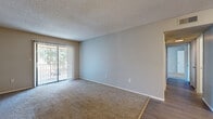 Located at 919 Ballard St in Altamonte Springs, Florida, this single-floor residence offers a practical and comfortable layout with consistent finishes throughout. The living area is generously sized, featuring plush wall-to-wall carpeting, neutral-toned walls, and a textured ceiling. A full-height sliding glass door fitted with vertical blinds opens to an outdoor patio, allowing natural light to fill the space while providing views of surrounding greenery. The transition from the carpeted living area to hard surface flooring marks the entry into the kitchen and utility zones. The kitchen is equipped with white cabinetry, speckled quartz-style countertops, a stainless steel dishwasher, and access to a dedicated pantry or storage closet with built-in shelving. The bedrooms continue the carpeted flooring and neutral color palette, each benefiting from windows with outdoor views and ample wall space. One bedroom features a large window overlooking a balcony area with tree views. The bathrooms include a single-sink vanity with a speckled countertop and white cabinetry, a full tub-shower combination, and wood-look vinyl flooring. Overall, the residence presents a clean, move-in ready environment with a cohesive and understated aesthetic throughout.