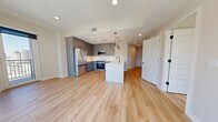 Unit 1100 at 855 N. Broadway is a thoughtfully designed 870-square-foot, two-bedroom, two-bathroom high-rise condominium located in Denver, CO. The open-concept layout features light hardwood flooring throughout, creating a cohesive and airy feel across all living spaces. Floor-to-ceiling windows in the living room and bedrooms flood the unit with natural light while offering striking panoramic views of the Denver cityscape and surrounding mountains. The kitchen is outfitted with gray shaker cabinetry, white quartz countertops, stainless steel appliances including a refrigerator, range, and microwave, and a peninsula with a built-in sink and pendant lighting above. Both bathrooms feature a clean, contemporary aesthetic with white square-tiled tub-surround showers, large-format tile flooring, gray vanities with white countertops, and matte black fixtures. The primary bedroom measures 120 square feet and benefits from expansive windows and a dedicated walk-in closet with dual hanging rods. The second bedroom also receives generous natural light through its large window. Two additional closets provide ample storage throughout the unit. Recessed lighting and neutral wall tones complete the modern, move-in-ready atmosphere of this urban residence.