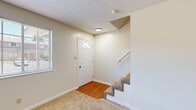 This two-story home in Parkersburg, WV is thoughtfully laid out across two floors, offering a comfortable and functional living experience. The main level features a welcoming entryway with a paneled front door accented by a transom window that lets in natural light, opening to a carpeted living area with neutral walls and a textured ceiling. Adjacent to the living room, the kitchen is well-appointed with rich dark wood cabinetry, green countertops, warm hardwood-style flooring, and white appliances including a gas range, dishwasher, and refrigerator, all complemented by a window over the sink. A staircase with a handrail leads to the upper level, where two carpeted bedrooms await. The spacious primary bedroom includes a sliding closet and an additional door for extra storage, while the second bedroom also features its own closet. The full bathroom on the upper floor includes a vanity with a marbled countertop, a toilet, and a tub-shower combination with white surround and a distinctive light blue tub, set on hardwood-style flooring. Throughout the home, three closets provide generous storage. Neutral tones, carpet upstairs, and hard-surface flooring on the main level create a clean, move-in-ready aesthetic.