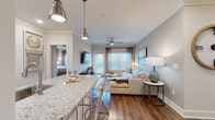 This thoughtfully designed single-floor residence blends modern elegance with comfortable living across a well-planned open layout. Rich hardwood flooring flows throughout, anchoring each room with warmth and continuity.

The kitchen is a standout feature, outfitted with crisp white shaker cabinetry, granite countertops, a marble-tiled backsplash, stainless steel appliances, and under-cabinet lighting. A granite-topped peninsula with seating provides an ideal space for casual dining, illuminated by stylish pendant lights overhead. A built-in wine rack adds a refined touch.

The open-concept living area is bright and inviting, with crown molding, a ceiling fan, and large windows that fill the space with natural light. The dining nook offers a cozy retreat with built-in shelving and space for an intimate table setting.

The primary bedroom is a serene escape, featuring a generous window with outdoor views, crown molding, and an en-suite bathroom with a dual-sink granite vanity, white cabinetry, and access to a walk-in closet. A second well-proportioned bedroom benefits from its own ceiling fan and natural light. The guest bathroom mirrors the same refined finishes, with a granite-topped white vanity and framed mirror. Every detail reflects a consistent commitment to quality and style throughout the home.