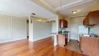 Located in Chicago's historic Hyde Park neighborhood, this single-floor unit at 1374 E 53rd St showcases timeless architectural character throughout. The main living area is a standout, featuring warm-toned hardwood floors, elegant crown molding, and classic wainscoting panels that lend a refined, traditional aesthetic to the walls. Multiple double-hung windows flood the space with natural light and offer views of the surrounding neighborhood, while a ceiling fan adds comfort overhead. Cast-iron radiators punctuate several rooms, nodding to the building's storied history.

The open layout connects the living area to a kitchen peninsula with granite-style countertops, providing a casual breakfast bar between the living and cooking spaces. The galley kitchen is fully equipped with rich wood cabinetry, matching granite-tone countertops, a gas range, and a full-size refrigerator, offering ample storage and prep space in an efficient layout. Tile flooring grounds the kitchen area, creating a clean transition from the hardwood in the main rooms.

The bathroom is bright and functional, featuring tile flooring, a soaking bathtub with shower, a wood-toned vanity, and a window that invites natural light. Throughout the unit, beamed ceilings and thoughtful architectural detailing reinforce the classic Chicago character of this well-appointed space.