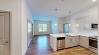 Located at 1100 Cricket Lane in East Walpole, MA, this well-appointed 2-bedroom, 2-bathroom unit offers a thoughtfully designed single-floor layout. The kitchen is a standout feature, showcasing shaker-style cabinetry in a soft gray finish, a white quartz peninsula with an undermount sink, stainless steel appliances including a refrigerator, range, microwave, and dishwasher, and warm hardwood-style flooring — all illuminated by pendant lighting and recessed fixtures. Both bedrooms are carpeted and filled with natural light through multiple windows with blinds, providing a calm and comfortable atmosphere. The primary bedroom is generously sized and connects to a dedicated closet outfitted with wire shelving for organized storage. The bathrooms feature shaker-style vanities with white quartz countertops, framed mirrors, and tub-shower combinations finished with classic white subway tile. Light wood-tone flooring runs through the bathrooms, complementing the clean, neutral palette found throughout the unit. Soft, neutral wall tones and gray-paneled interior doors tie the space together with a cohesive, contemporary aesthetic.