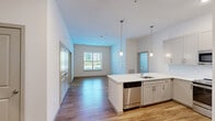 Located at 1100 Cricket Lane in East Walpole, MA, this well-appointed 2-bedroom, 2-bathroom unit offers a thoughtfully designed single-floor layout. The kitchen is a standout feature, showcasing shaker-style cabinetry in a soft gray finish, a white quartz peninsula with an undermount sink, stainless steel appliances including a refrigerator, range, microwave, and dishwasher, and warm hardwood-style flooring — all illuminated by pendant lighting and recessed fixtures. Both bedrooms are carpeted and filled with natural light through multiple windows with blinds, providing a calm and comfortable atmosphere. The primary bedroom is generously sized and connects to a dedicated closet outfitted with wire shelving for organized storage. The bathrooms feature shaker-style vanities with white quartz countertops, framed mirrors, and tub-shower combinations finished with classic white subway tile. Light wood-tone flooring runs through the bathrooms, complementing the clean, neutral palette found throughout the unit. Soft, neutral wall tones and gray-paneled interior doors tie the space together with a cohesive, contemporary aesthetic.