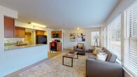 This well-appointed 2-bedroom, 2-bathroom residence is laid out on a single floor, offering a functional and comfortable living experience. The open-concept living area is anchored by large windows that invite generous natural light, with light wood-style flooring flowing throughout. The kitchen is thoughtfully designed with warm medium-tone wood cabinetry, granite countertops, a breakfast bar peninsula, and black appliances including a refrigerator and range. A dedicated laundry area with a washer and dryer is conveniently located just off the kitchen. The living room provides ample space for relaxing and entertaining, with multiple windows offering views of the surrounding neighborhood. Both bedrooms are comfortably sized, each featuring ceiling fans, natural light from well-placed windows, and access to closet storage — one bedroom includes a walk-in closet. Each of the two bathrooms is finished with granite countertops, warm wood vanity cabinetry, and large mirrors, reflecting a consistent and cohesive design aesthetic. The neutral color palette throughout the home creates a bright, versatile atmosphere suited to a variety of interior styles.