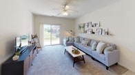 This single-story residence offers a thoughtfully designed layout with two bedrooms, two bathrooms, a kitchen, dining area, and a generous living space. The kitchen is outfitted with white cabinetry accented by wood-toned trim, dark countertops, white appliances including a refrigerator, electric range, and dishwasher, and durable tile flooring. Ample upper and lower cabinet storage ensures practical functionality throughout the space.

The living room is carpeted and features a ceiling fan with light fixture and a sliding glass door that opens to an outdoor view, filling the room with natural light. A wall-mounted display shelf adds a decorative element to the neutral-toned walls. Adjacent to the living room, the dining area provides a quiet, carpeted space for meals.

Both bedrooms are carpeted and feature neutral walls with natural light from windows. One bedroom includes a closet, while both offer comfortable proportions for furnishing. The two bathrooms are consistent in design, each featuring a vanity with white cabinetry, dark countertops, a large mirror, and tile flooring. One bathroom includes a shower-tub combination, while the other features a vanity-focused layout.