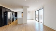 Located at 214 E Florida St in Milwaukee's vibrant Walker's Point neighborhood, this modern single-floor residence delivers a clean, contemporary aesthetic throughout. The open-concept living and kitchen area serves as the heart of the space, where light hardwood flooring flows seamlessly underfoot and recessed lighting illuminates the crisp white walls and ceilings. Large sliding glass doors lead to a private outdoor area, flooding the living space with natural light and providing direct exterior access.

The kitchen is thoughtfully appointed with floor-to-ceiling dark cabinetry, stainless steel appliances including a range, microwave, and refrigerator, and a subway tile backsplash that adds textural contrast. A generous island with a light quartz countertop provides additional workspace and casual seating potential. A stylish barn door accents the transitional space nearby, adding an industrial touch.

The bedrooms are bright and well-proportioned, each featuring hardwood flooring and windows that invite natural light, with one bedroom offering views of the surrounding Milwaukee cityscape. The bathrooms are finished with large-format stone tile flooring, dark vanity cabinetry, white countertops, and glass-enclosed showers, maintaining the space's cohesive modern design language throughout.