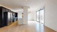 Located at 214 E Florida St in Milwaukee's vibrant Walker's Point neighborhood, this modern single-floor residence delivers a clean, contemporary aesthetic throughout. The open-concept living and kitchen area serves as the heart of the space, where light hardwood flooring flows seamlessly underfoot and recessed lighting illuminates the crisp white walls and ceilings. Large sliding glass doors lead to a private outdoor area, flooding the living space with natural light and providing direct exterior access.

The kitchen is thoughtfully appointed with floor-to-ceiling dark cabinetry, stainless steel appliances including a range, microwave, and refrigerator, and a subway tile backsplash that adds textural contrast. A generous island with a light quartz countertop provides additional workspace and casual seating potential. A stylish barn door accents the transitional space nearby, adding an industrial touch.

The bedrooms are bright and well-proportioned, each featuring hardwood flooring and windows that invite natural light, with one bedroom offering views of the surrounding Milwaukee cityscape. The bathrooms are finished with large-format stone tile flooring, dark vanity cabinetry, white countertops, and glass-enclosed showers, maintaining the space's cohesive modern design language throughout.