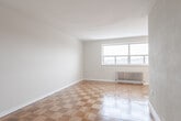 Located on the fifth floor at 1309 Wilson Ave in Toronto's Wilson Heights neighbourhood, this one-bedroom, one-bathroom unit offers a practical and well-organized layout across a single floor. Warm parquet flooring in a classic checkerboard pattern flows throughout the main living areas, hallway, and bedroom, lending a timeless character to the space.

The combined dining and living area provides an open, versatile space filled with natural light, with a view into the adjacent kitchen. The kitchen features white cabinetry with ample storage, white tile backsplash, tile flooring, and a full-size stainless steel refrigerator — delivering both functionality and a clean aesthetic.

The bedroom is a comfortable, well-proportioned room with a large window that brings in natural light and offers views of the surrounding neighbourhood. A radiator beneath the window provides reliable heating, and a set of double closet doors offers convenient built-in storage.

The bathroom is finished in a crisp, all-white palette with a combined tub and shower, white tile surround, a modern floating vanity with an integrated sink, and a mirror — creating a clean and refreshing space.

A hallway connects the main rooms efficiently, rounding out a thoughtfully arranged unit well-suited for comfortable urban living in Toronto.
