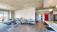 This contemporary 3-bedroom, 3-bathroom residence offers a thoughtfully designed single-floor layout that balances open communal spaces with private retreats. The open-concept living and kitchen area serves as the heart of the home, immediately drawing attention with its signature exposed concrete ceiling — an industrial architectural detail that lends the space a distinctive urban character. Wide-plank, hardwood-style flooring runs throughout, unifying each room with warmth and continuity.

The living room is generously proportioned, anchored by large floor-to-ceiling windows that flood the space with natural light and frame impressive city and skyline views. The kitchen is well-appointed with sleek white cabinetry extending to the ceiling, light quartz countertops, a large center island with an undermount sink, and a full suite of stainless steel appliances including a refrigerator, range, and built-in microwave. In-unit stacked washer and dryer add convenience.

The spacious primary bedroom also benefits from expansive windows with panoramic views, continuing the exposed concrete ceiling aesthetic. The additional bedrooms are well-sized with neutral finishes and ample lighting. Each of the three bathrooms features clean, modern fixtures with white vanities and glass-enclosed showers. The entrance and hallways provide smooth transitions between all areas of this well-designed residence.