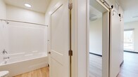 Located on Hillview Way in Missoula, Montana, this single-floor unit offers a thoughtfully designed layout that maximizes its compact footprint. The interior is unified by light hardwood flooring throughout, creating a warm, cohesive aesthetic that extends from room to room.

The kitchen is a standout feature, outfitted with modern flat-panel cabinetry in a light wood-grain finish accented by matte black hardware. A full suite of stainless steel appliances — including a gas range, over-the-range microwave, dishwasher, and refrigerator — lines a single wall, complemented by a clean white countertop and a stainless steel sink. Recessed lighting and a large window illuminate the adjacent living area, which benefits from views of surrounding greenery and ample natural light through tall windows with roller shades.

The bathroom is clean and functional, featuring a full tub-shower combination, a toilet, and a wood-toned vanity with a sink. White shaker-style interior doors with brushed nickel hardware are consistent throughout. Neutral, light-toned walls and white trim contribute to a bright, contemporary ambiance. The overall design reflects a modern, efficient aesthetic well-suited to Missoula's active lifestyle.