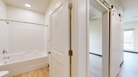 Located on Hillview Way in Missoula, Montana, this single-floor unit offers a thoughtfully designed layout that maximizes its compact footprint. The interior is unified by light hardwood flooring throughout, creating a warm, cohesive aesthetic that extends from room to room.

The kitchen is a standout feature, outfitted with modern flat-panel cabinetry in a light wood-grain finish accented by matte black hardware. A full suite of stainless steel appliances — including a gas range, over-the-range microwave, dishwasher, and refrigerator — lines a single wall, complemented by a clean white countertop and a stainless steel sink. Recessed lighting and a large window illuminate the adjacent living area, which benefits from views of surrounding greenery and ample natural light through tall windows with roller shades.

The bathroom is clean and functional, featuring a full tub-shower combination, a toilet, and a wood-toned vanity with a sink. White shaker-style interior doors with brushed nickel hardware are consistent throughout. Neutral, light-toned walls and white trim contribute to a bright, contemporary ambiance. The overall design reflects a modern, efficient aesthetic well-suited to Missoula's active lifestyle.