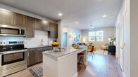 This single-floor, 2-bedroom, 2-bathroom unit offers a thoughtfully designed open-concept layout with modern finishes throughout. The kitchen serves as a focal point, featuring rich dark-brown shaker-style cabinetry, granite countertops, a classic white subway tile backsplash, and a full suite of stainless steel appliances including a refrigerator, range, microwave, and dishwasher. A granite-topped island with bar seating provides additional workspace and transitions seamlessly into the combined dining and living area. The living room is well-lit by a large window with outdoor views and is equipped with a ceiling fan. Wood-style flooring runs consistently throughout the unit, enhancing the cohesive aesthetic.

Both bedrooms are bright and airy, each featuring windows that bring in natural light, ceiling fans, and durable wood-style flooring. The primary bedroom connects directly to a full bathroom outfitted with a granite-topped vanity with dark cabinetry, and a soaking tub with white subway tile surround. A dedicated walk-in closet with wire shelving provides generous storage. The second bathroom mirrors the same refined design language. Neutral wall tones and clean architectural lines contribute to a contemporary, move-in-ready ambiance throughout.