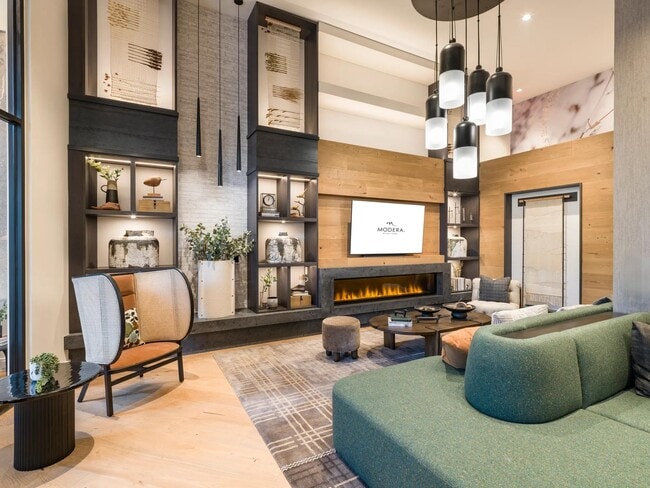 Relax fireside in this cozy and modern resident lounge, perfect for quiet mornings or unwinding with friends. - Modera Falls Church