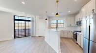 Located at 274 South Ave in Fanwood, NJ, this thoughtfully designed 2-bedroom, 2-bathroom residence offers a clean, modern aesthetic with high-quality finishes throughout. The open-concept kitchen is a standout feature, showcasing white shaker cabinetry with matte black hardware, quartz countertops, a subway tile backsplash, stainless steel appliances, and a central island with beadboard paneling topped by stylish gold-accented pendant lights. Light hardwood flooring flows seamlessly throughout the living areas, enhancing the bright, airy feel. A set of bold black-framed sliding glass doors leads to a private balcony, allowing natural light to pour into the living space. The primary bedroom is generously sized and features direct balcony access, a ceiling fan, and ample closet space. The second bedroom is equally well-appointed with a ceiling fan, a large window, and a double-door closet. Both bathrooms are finished with white cabinetry, quartz vanity tops, and LED-backlit mirrors for a sleek, contemporary look. Additional highlights include a den, a dedicated laundry room, a utility room, a hallway, and five closets offering abundant storage. This residence combines functional design with modern style in a well-connected New Jersey location.