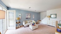 Located at 125 Essex Ave E in Avenel, NJ, this multi-level home spans three floors and features one bedroom, three bathrooms, a dedicated office, and two closets. The main living level offers a combined living room, dining room, and kitchen that together form a bright, open hub for daily life. The living room is finished with plush carpeting and soft blue accent walls, and a sliding glass door invites natural light while providing outdoor access. The kitchen is well-appointed with rich dark wood cabinetry, light stone countertops, hardwood-style flooring, and a full suite of stainless steel appliances. The adjacent dining area benefits from a large window overlooking the outdoors and continues the warm hardwood flooring. A staircase with natural wood treads and white risers connects the floors with clean, classic detailing. The primary bedroom is a comfortable retreat featuring hardwood flooring and neutral tones. The dedicated office on the upper floor showcases vaulted ceilings and a bright window, making it an inspiring workspace. Three bathrooms — including one with a walk-in glass shower and tiled finishes — provide ample convenience. Two closets and a hallway complete the well-organized floor plan, making this a highly functional and attractive multi-level home.
