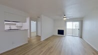This single-story residence offers three bedrooms and two full bathrooms within a thoughtfully arranged floor plan. Light wood-style flooring runs consistently throughout the unit, contributing to a bright, cohesive aesthetic across all rooms.

The open-concept living and kitchen area serves as the central hub of the home. The living room features a ceiling fan, a tiled fireplace, and a sliding glass door that opens to a private balcony, allowing natural light to fill the space. The adjacent kitchen is equipped with white shaker-style cabinetry, marble-look countertops, a black electric range with overhead ventilation, and a stainless steel refrigerator. A pass-through counter connects the kitchen to the living area.

The primary bedroom offers a ceiling fan and a window with natural light. The two additional bedrooms feature the same light flooring and neutral white walls. A hallway and closet provide additional storage and circulation between rooms.

Both bathrooms are finished with white vanity cabinetry, marble-look countertops, large mirrors, and tub-shower combinations, maintaining a clean and consistent design throughout the unit.