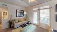 This single-floor residence offers a thoughtfully organized layout that balances functionality and comfort throughout its interconnected living spaces. The kitchen is equipped with white cabinetry, a stainless steel sink, a full-size refrigerator, an electric range with over-the-range microwave, and a dishwasher. Track lighting illuminates the workspace, while wood-look flooring adds warmth underfoot. A peninsula counter connects the kitchen to the adjacent dining area, which features a pendant light fixture overhead, a large window with natural light, and neutral carpeting.

The living room is bright and welcoming, benefiting from a glass-paneled exterior door with transom window that introduces outdoor views and natural light. Crown molding and a ceiling fan with a decorative light fixture are notable architectural details. The bedroom offers a carpeted floor, natural light from a window with draping, and warm-toned walls that contribute to a calm ambiance.

The bathroom includes a single-sink vanity with storage below, a large mirror, and a shower-tub combination with a curved curtain rod. A dedicated in-unit laundry area accommodates a full-size washer and dryer with wire shelving above for additional storage.