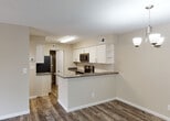 Located at 9873 Lawrence Rd in Boynton Beach, Florida, this single-floor residence offers a clean, modern aesthetic with thoughtfully updated finishes throughout. The open-concept living and dining area features durable wood-look vinyl plank flooring and neutral warm-toned walls, creating a bright and welcoming atmosphere. A ceiling fan adds comfort to the living space, which also benefits from sliding glass door access that brings in natural light.

The kitchen is a standout feature, designed with white shaker-style cabinetry, dark gray countertops, and a classic white subway tile backsplash. Stainless steel appliances — including a refrigerator, electric range, over-the-range microwave, and dishwasher — provide a sleek, functional workspace. A peninsula with counter seating connects the kitchen to the main living area seamlessly.

The bedrooms are carpeted for comfort, with one room offering a window view to the outdoors. Neutral tones carry throughout, lending a cohesive and move-in-ready feel. The bathroom is well-appointed with wood-look vinyl flooring, white cabinetry with gray countertops, a combined tub and shower with a curved rod, and clean white tile surround. A louvered utility closet is accessible from the kitchen area, adding practical storage to this well-organized layout.