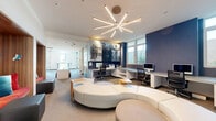 Located at 505 W 31st St in Los Angeles, CA, this single-floor collaborative workspace offers a thoughtfully designed environment that balances productivity with creative energy. The open layout is anchored by a striking sculptural starburst chandelier that casts dynamic light across the central lounge area, which features a curved, modular white sectional sofa and ottomans ideal for informal gatherings or relaxed work sessions.

Along one wall, a series of warm wood-paneled alcove seating nooks are adorned with bold geometric wallpaper in red, blue, and orange — providing semi-private spots for focused work or casual meetings. A row of glass-walled conference rooms, each numbered and wrapped in vibrant, large-scale graphic murals, lines the perimeter and accommodates small group collaboration.

The workstation area features built-in desking along a navy blue accent wall, complete with desktop computers and ample storage, bathed in natural light from a generous bank of windows overlooking the outdoors. Large-scale black-and-white photographic murals add an artistic, editorial character to the space.

Private offices with glass partitions offer additional enclosed work areas, while open worktables with compact seating serve as versatile touchdown stations. Throughout, the design integrates bold color, curated artwork, and flexible furnishings to create an engaging, modern professional environment.