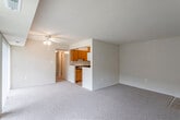 This single-floor unit offers a practical and functional layout designed to maximize usable space. The living area is generously sized, finished with neutral-toned carpet, and features a ceiling fan overhead. A sliding glass door along one wall allows natural light to fill the room while providing direct access to the outdoors. The entry door opens into this main living space, which transitions seamlessly toward the kitchen pass-through area.

The galley-style kitchen is efficiently arranged with warm oak cabinetry lining both sides, dark speckled countertops, a stainless steel sink, and white appliances including a gas range, refrigerator, and microwave. Light tile flooring completes the kitchen, contrasting with the carpeted living spaces.

The bedrooms are carpeted and finished in neutral tones, each offering a closet with built-in shelving. One bedroom features a wide window with outdoor views, providing natural light and a sense of openness. Additional rooms offer quieter, more enclosed settings suitable for various uses.

The bathroom includes a full tub and shower combination with white tile surround, a toilet, and a wood-trimmed vanity with a white countertop and sink, complemented by mosaic tile flooring. Throughout, the unit maintains a clean, understated aesthetic with consistent neutral finishes.