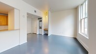 Located in the heart of downtown Jacksonville, FL, Unit 208 at 11 East Forsyth Street is a thoughtfully laid-out single-floor residence featuring a combined kitchen and living area, a full bathroom, and a dedicated closet. The living space is defined by polished concrete floors in a cool blue-grey tone that run seamlessly throughout, contributing to a clean, modern aesthetic. Large, multi-pane windows flood the living area with abundant natural light and offer views of the surrounding urban streetscape, while a ceiling fan provides year-round comfort. The open-concept kitchen is equipped with warm honey-toned wood cabinetry, light stone-finish countertops, and black appliances including a refrigerator, electric range with overhead microwave, and dishwasher. A raised breakfast bar counter separates the kitchen from the living area, enhancing the sense of openness. A built-in desk nook adds functional workspace, and a stacked in-unit washer and dryer provide added convenience. The bathroom features a dual-sink vanity with matching wood cabinetry, a wide mirror with overhead lighting, and access to a walk-in closet. The overall ambiance is bright, clean, and urban, making this a practical and comfortable downtown residence.