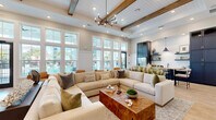 Located in Venice, Florida, this single-story community clubhouse offers a thoughtfully designed gathering space that blends coastal charm with modern sophistication. The welcoming entrance lobby features herringbone wood-panel accent walls, light hardwood flooring, bold navy cabinetry, and a striking pendant light, setting an inviting tone from the moment you step inside. A curated seating area with rounded lounge chairs provides a comfortable spot for casual conversations.

The expansive main lounge is anchored by soaring ceilings with exposed wood beams and shiplap detailing, a dramatic chandelier, and a wall of oversized windows that flood the space with natural light and frame views of the outdoor pool area. A generously sized sectional sofa surrounds a live-edge wood coffee table, creating an ideal setting for relaxation or socializing. A dedicated media nook showcases a bold, artistic tile feature wall in layered blue tones with navy built-in cabinetry below.

A secondary sitting area offers intimate seating around a round marble-top table, bathed in natural light from tall windows. The kitchenette is outfitted with quartz countertops, a stainless steel undermount sink, matte black fixtures, a white subway tile backsplash, and navy open shelving. A fully equipped fitness center with glass door access completes this well-appointed community facility.