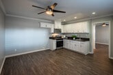 This single-floor residence at 901 S Harbor Blvd in Santa Ana, California offers a clean, modern aesthetic throughout. The kitchen is a standout feature, showcasing crisp white shaker-style cabinetry with brushed nickel hardware, rich dark granite countertops, and a stainless steel sink. Stainless steel appliances, including a gas range and over-the-range microwave, complete the functional and stylish cooking space. Recessed lighting and crown molding add refined detail to the kitchen ceiling, while a ceiling fan enhances airflow in the adjoining living area. Wood-look luxury vinyl plank flooring runs consistently throughout the home, providing both durability and a warm, cohesive feel. The bedroom is generously sized, featuring a ceiling fan, neutral gray walls, and floor-to-ceiling mirrored sliding closet doors that amplify the sense of space and reflect natural light. The bathroom is thoughtfully appointed with a full tub and shower combination, grab bars for accessibility, dark granite vanity countertops, and a clean white palette. Natural light filters in through multiple windows, contributing to the home's bright and welcoming ambiance. The open layout and consistent finishes create a comfortable, move-in-ready living environment.