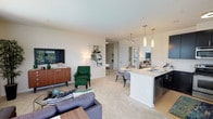 This single-floor residence offers a thoughtfully designed open-concept layout that seamlessly connects the living, dining, and kitchen areas. The living room is generously proportioned, featuring large windows that invite abundant natural light and views of surrounding greenery. Plush carpeting, neutral walls, and a ceiling fan contribute to a comfortable atmosphere throughout the space.

The kitchen is a functional standout, featuring dark cabinetry contrasted by white countertops, stainless steel appliances including a refrigerator, range, microwave, and dishwasher, and hardwood-style flooring. A peninsula with a double sink and pendant lighting above serves as both a prep area and casual dining space.

The residence includes multiple bedrooms, each carpeted and equipped with ceiling fans. One bedroom features a bold green accent wall paired with large windows offering outdoor views, adding a distinctive character to the space. Additional bedrooms maintain a neutral palette with ample natural light.

Two full bathrooms mirror each other in design, each featuring dark vanity cabinetry, white countertops, tile flooring, and a tub-shower combination, providing practical and clean-lined functionality throughout.