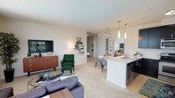This single-floor residence offers a thoughtfully designed open-concept layout that seamlessly connects the living, dining, and kitchen areas. The living room is generously proportioned, featuring large windows that invite abundant natural light and views of surrounding greenery. Plush carpeting, neutral walls, and a ceiling fan contribute to a comfortable atmosphere throughout the space.

The kitchen is a functional standout, featuring dark cabinetry contrasted by white countertops, stainless steel appliances including a refrigerator, range, microwave, and dishwasher, and hardwood-style flooring. A peninsula with a double sink and pendant lighting above serves as both a prep area and casual dining space.

The residence includes multiple bedrooms, each carpeted and equipped with ceiling fans. One bedroom features a bold green accent wall paired with large windows offering outdoor views, adding a distinctive character to the space. Additional bedrooms maintain a neutral palette with ample natural light.

Two full bathrooms mirror each other in design, each featuring dark vanity cabinetry, white countertops, tile flooring, and a tub-shower combination, providing practical and clean-lined functionality throughout.