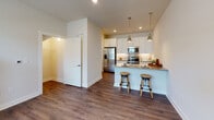 Located at 3215 in Wilmington, NC, this two-story residence offers a well-designed layout that distributes living and sleeping spaces across two distinct levels, connected by a staircase visible in the 3D overview of the home.

The main level centers around an open-concept kitchen and living area. The kitchen is outfitted with crisp white shaker-style cabinetry extending to the ceiling, granite countertops, and a full suite of stainless steel appliances including a French door refrigerator, electric range, and built-in microwave. A peninsula with seating provides casual dining space, illuminated by pendant lighting overhead. Dark hardwood-style flooring runs throughout the main level, adding warmth and continuity. A convenient powder room with a pedestal sink and framed mirror is also found on this floor.

Upstairs, the bedrooms feature plush carpeting and neutral wall tones, creating a calm, restful atmosphere. The primary bedroom connects directly to an en-suite bathroom and a walk-in closet with built-in shelving. The full bathroom includes a tub-shower combination, granite-topped vanity with white cabinetry, and dark wood-style flooring. Additional bedrooms are generously sized with natural light from windows fitted with blinds.