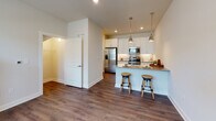 Located at 3215 in Wilmington, NC, this two-story residence offers a well-designed layout that distributes living and sleeping spaces across two distinct levels, connected by a staircase visible in the 3D overview of the home.

The main level centers around an open-concept kitchen and living area. The kitchen is outfitted with crisp white shaker-style cabinetry extending to the ceiling, granite countertops, and a full suite of stainless steel appliances including a French door refrigerator, electric range, and built-in microwave. A peninsula with seating provides casual dining space, illuminated by pendant lighting overhead. Dark hardwood-style flooring runs throughout the main level, adding warmth and continuity. A convenient powder room with a pedestal sink and framed mirror is also found on this floor.

Upstairs, the bedrooms feature plush carpeting and neutral wall tones, creating a calm, restful atmosphere. The primary bedroom connects directly to an en-suite bathroom and a walk-in closet with built-in shelving. The full bathroom includes a tub-shower combination, granite-topped vanity with white cabinetry, and dark wood-style flooring. Additional bedrooms are generously sized with natural light from windows fitted with blinds.
