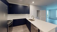 Located at 138 N Beaudry Ave in Los Angeles, CA, this single-floor unit offers a thoughtfully designed interior with modern finishes throughout. The open-concept kitchen is a standout feature, showcasing bold navy blue cabinetry accented with gold hardware, crisp white quartz countertops, a marble-style tile backsplash, and stainless steel appliances including a refrigerator, microwave, and dishwasher. A gold-finish faucet over a stainless steel sink adds an elevated touch to the peninsula layout, which provides additional counter space and storage.

The living area is generously sized, featuring wood-look plank flooring, neutral walls, and natural light from blinds-covered windows. A dedicated in-unit laundry closet with louvered doors is conveniently situated adjacent to the living space. The bedrooms offer plush carpeting and windows that bring in natural light, providing a comfortable and quiet retreat.

The bathrooms are finished in a clean, contemporary style. One features a navy vanity with gold hardware, a white countertop, a lighted mirror, and a tub-shower combination. The second bathroom also includes a tub-shower with white tile surround. Wood-look flooring carries through both bathrooms, maintaining a cohesive aesthetic across the unit.