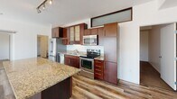 Located at 1724 W Lake St in Minneapolis's vibrant Uptown neighborhood, this single-floor unit offers a thoughtfully designed layout with contemporary finishes throughout. The open living area is bathed in natural light from large windows and floor-to-ceiling sliding glass doors that lead to a private balcony, where views of the surrounding urban streetscape provide a lively backdrop. Wood-style plank flooring runs through the main living and kitchen areas, lending warmth and cohesion to the space.

The kitchen is a standout feature, showcasing rich dark-wood cabinetry with frosted glass upper panels, granite countertops, a central island with additional prep space, and a full suite of stainless steel appliances including a refrigerator, electric range, built-in microwave, and dishwasher. Track lighting overhead adds a modern touch.

A wide, bright hallway connects the living areas to the bedrooms, which are finished with plush carpeting and ceiling fans. Each bedroom benefits from natural light and closet access. The bathroom is cleanly designed with tile flooring, a dark-wood vanity, white countertop, and tiled shower surround. The overall aesthetic is clean, modern, and move-in ready.