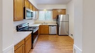 This two-floor residential space offers a functional and comfortable layout with a variety of thoughtfully designed rooms. The main living area is generously sized, featuring neutral wall-to-wall carpeting and a sliding glass door fitted with vertical blinds that opens to an outdoor patio, allowing natural light to fill the room. Adjacent to the living area, a secondary carpeted room provides flexible use as a dining space or additional lounge area, with an open view into the kitchen through an arched passageway.

The kitchen is well-appointed with warm honey-toned wood cabinetry, light countertops, and a full suite of stainless steel appliances including a refrigerator, dishwasher, and range with microwave. A window above the sink brings in natural light, while wood-look flooring adds warmth and durability underfoot.

The upper level houses the bedrooms, each carpeted and brightened by multiple windows with blinds. The primary bedroom features two side-by-side closets offering ample storage. Textured ceilings are consistent throughout the upper floor, adding a classic residential character.

The bathroom includes a wood-toned vanity with a white countertop, white tile wainscoting, and wood-look flooring, presenting a clean and practical design. Throughout the space, neutral tones and consistent finishes create a cohesive, move-in-ready atmosphere.